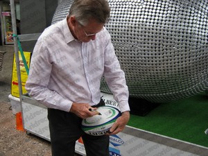 Sir John Walker signing rugby ball at the bottle cap sculpture launch 3rd December 2010